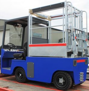 Porteur électrique bleu avec cabine latérale et plateforme arrière équipée d’une structure métallique modulable pour le transport ou la manutention sécurisée.