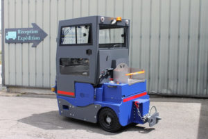Vue de dos d'un tracteur électrique avec 3 roues et 1 place assise. Il possède également un dispositif pour transporter des marchandises